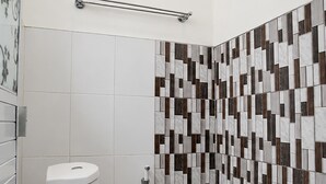 Ein Badezimmer mit Toilette, Dusche und einer Wand mit geometrischem Muster.