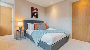 A bedroom with a bed, bedside table, lamp, and a framed picture on the wall. - Modern 2BR Apt in Leeds Arena Uni City Hub Stay (Leeds)