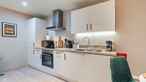 A modern kitchen with white cabinetry, a built-in oven, and a microwave. - Modern 2BR Apt in Leeds Arena Uni City Hub Stay (Leeds)