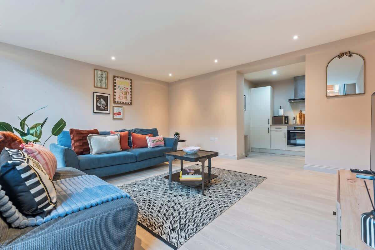 Een moderne woonkamer met een bank, salontafel en een keuken op de achtergrond.