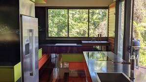 A modern kitchen with a large window, a built-in refrigerator, and a wooden floor. - Rainforest Meets Luxury - Infinity Pool Views (Cairns)