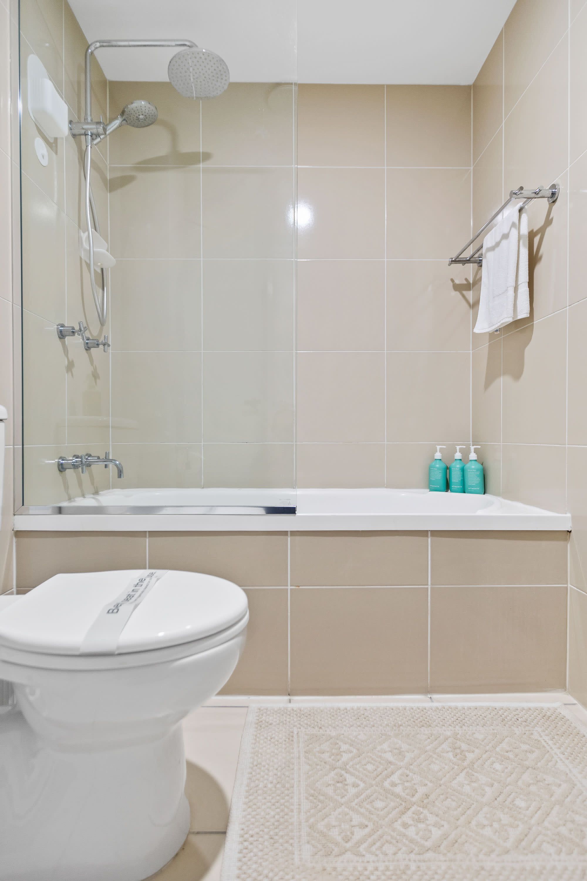 Een badkamer met douche, toilet en bad.