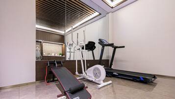 A gym with a treadmill, elliptical, and a bench press.
