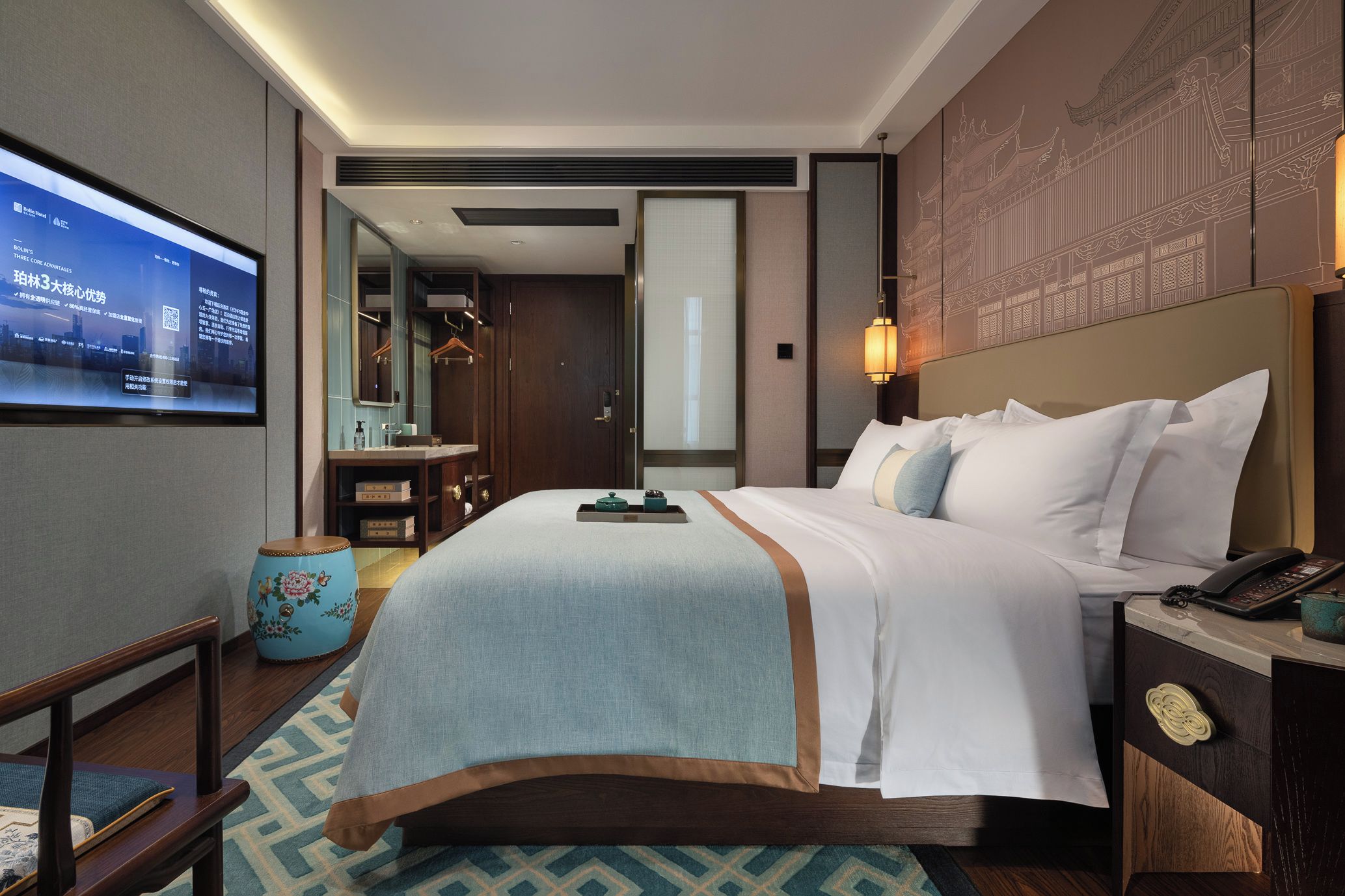 A hotel room with a bed, bedside table, lamp, and a television displaying a screen.