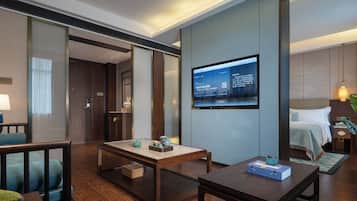 Habitación de hotel con cama, escritorio, televisión y zona de estar.