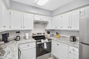 A modern kitchen with white cabinets, a stainless steel oven, a coffee maker, and a toaster. - Dalraida 3br Near Gunter Annex and Downtown (Montgomery)