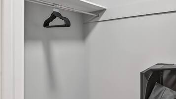 A closet with a hanging rod and a storage unit.