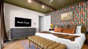 Ein Schlafzimmer mit einem Bett, einer Bank, einem Fernseher, einem Kleiderschrank und einer Wand mit Muster.