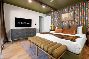 A bedroom with a bed, a bench, a TV, a wardrobe, and a patterned wall. - Golf Simulator Pool Sports Court Sleeps 24 (Mesa)