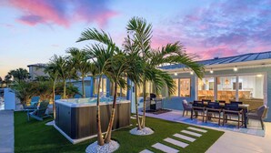 A modern outdoor patio with a hot tub, seating, and palm trees. - Private Dock Pool Hot Tub Puttputt Games (St. Petersburg)