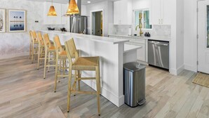 A modern kitchen with white cabinetry, stainless steel appliances, and a central island with bar stools. - Private Dock Pool Hot Tub Puttputt Games (St. Petersburg)