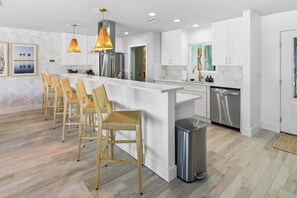 A modern kitchen with white cabinetry, stainless steel appliances, and a central island with bar stools. - Private Dock Pool Hot Tub Puttputt Games (St. Petersburg)
