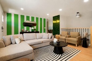 A modern living room with a sectional sofa, a round coffee table, and a striped rug. - Peak State Hot Tub Sauna Arcade (Littleton)