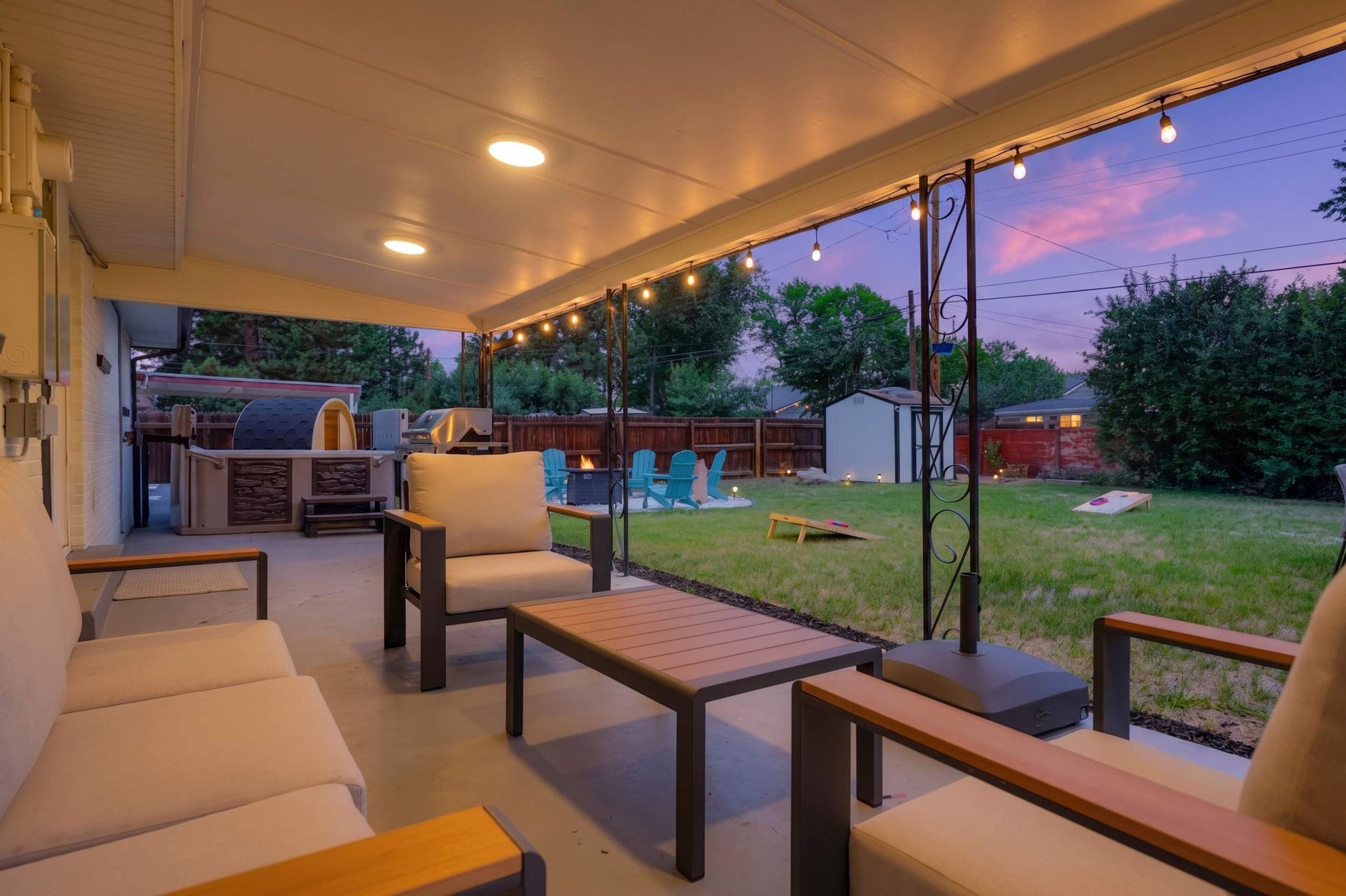 Un patio techado con mobiliario exterior, una parrilla de barbacoa y vistas al jardín trasero.