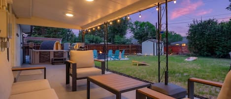 Un patio techado con mobiliario exterior, una parrilla de barbacoa y vistas al jardín trasero.