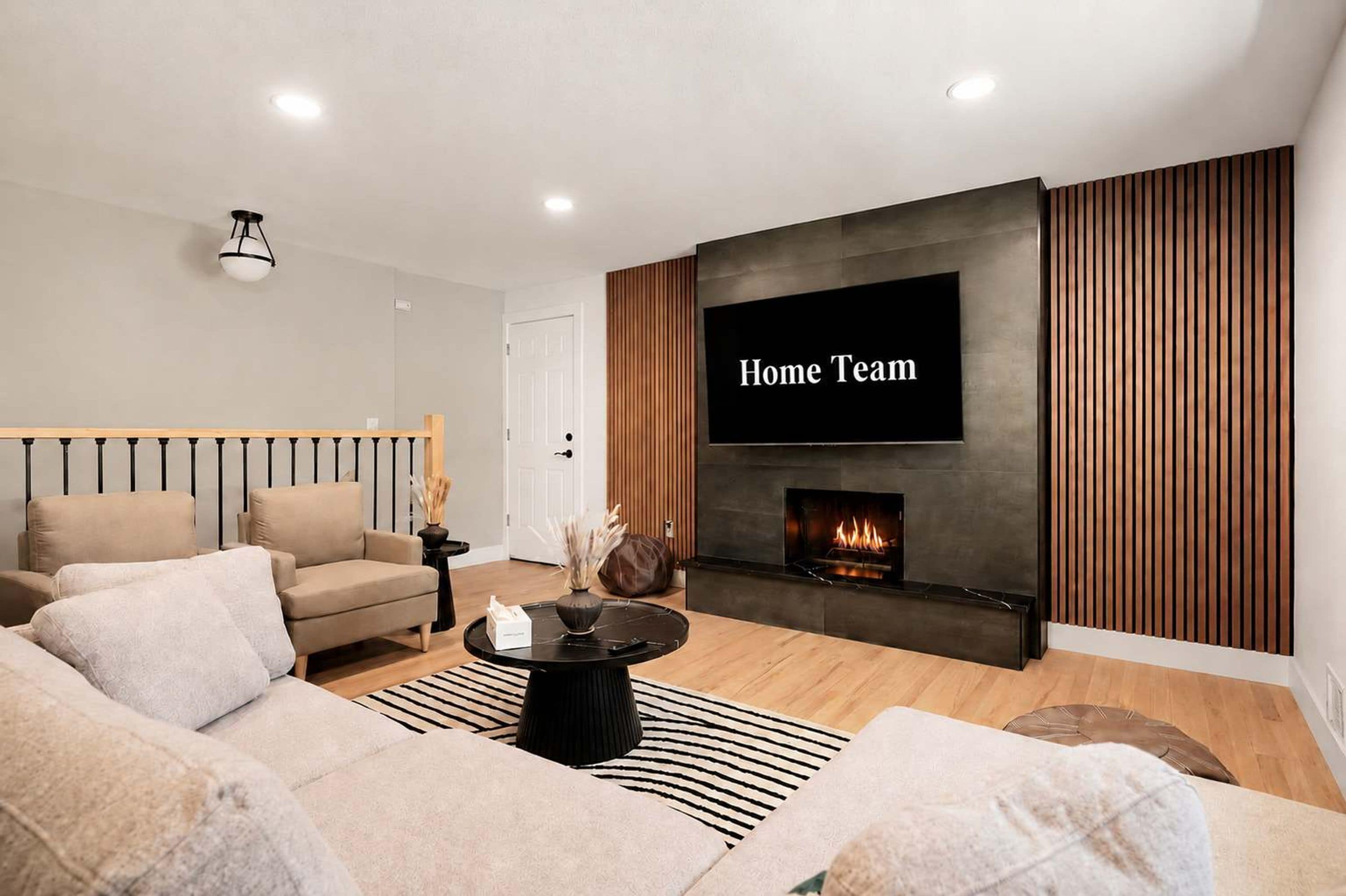 A modern living room with a sofa, a coffee table, a fireplace, and a TV mounted on the wall.