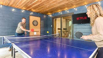 A ping pong table in a room with a dartboard and a sign indicating a Netflix service.