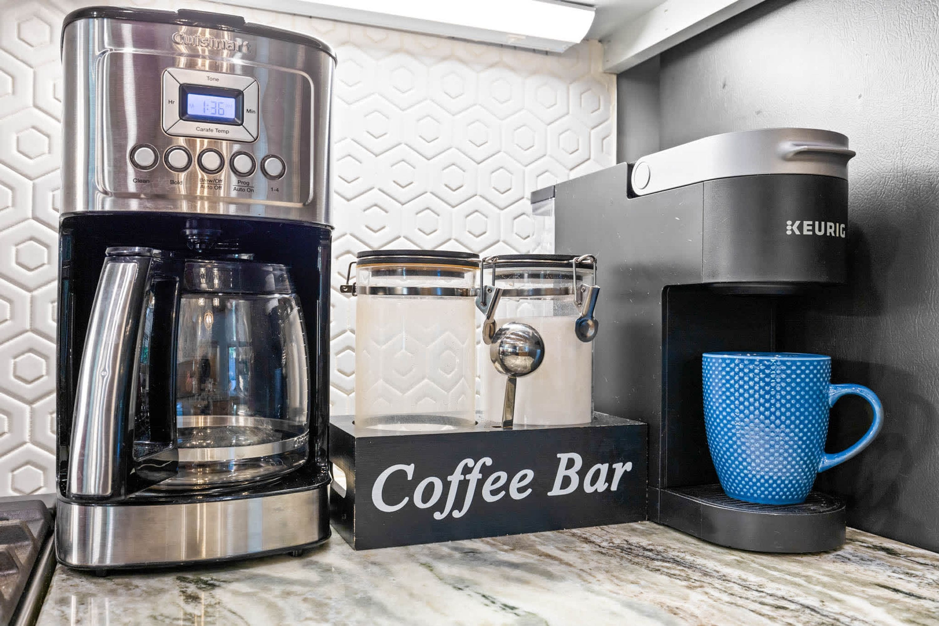 A coffee maker, a coffee grinder, and a coffee mug on a countertop.