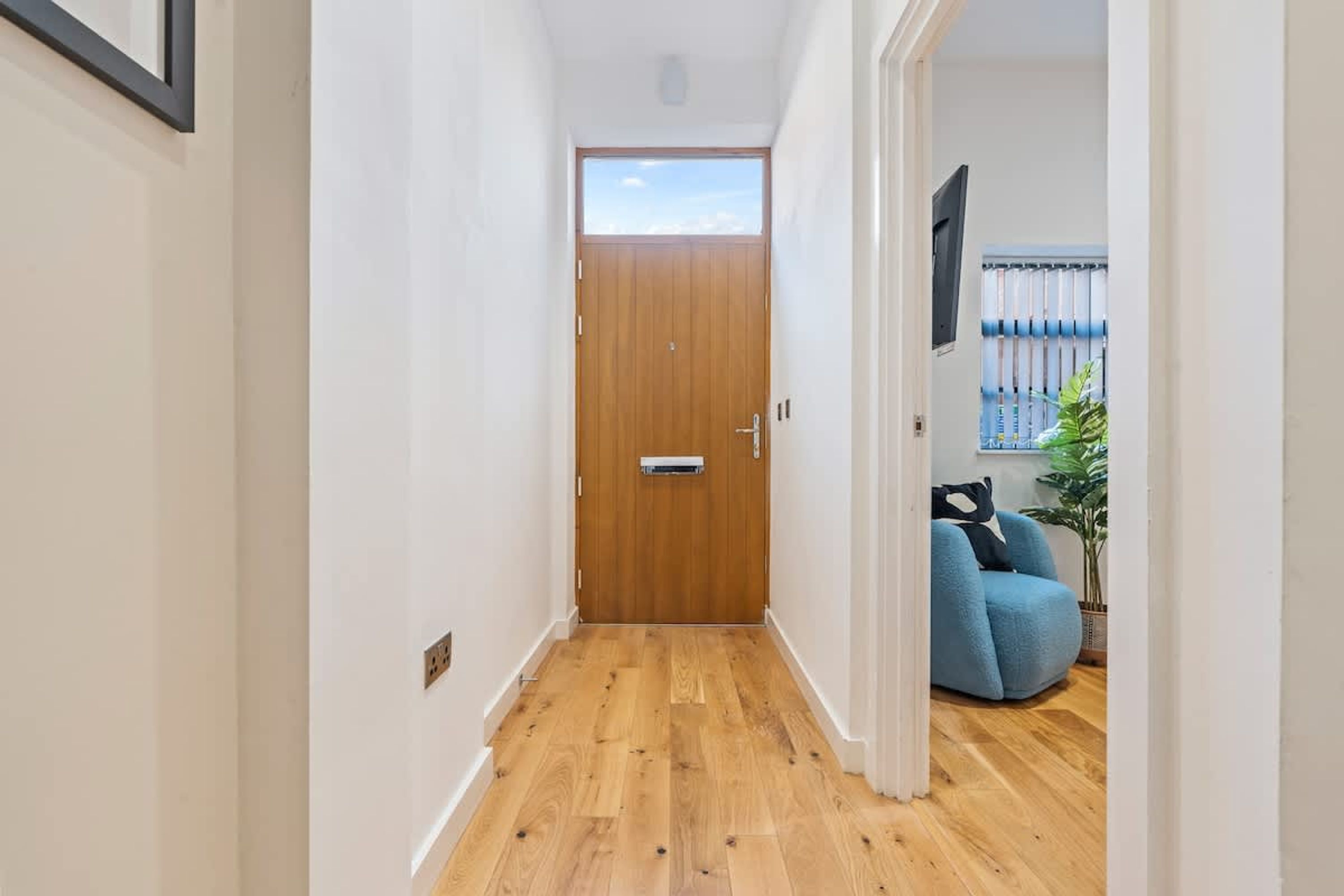 Un couloir étroit, doté d’un plancher en bois, mène à une porte également en bois.