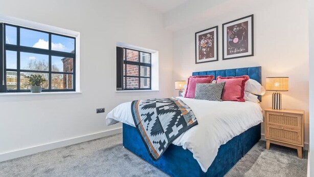 A bedroom with a bed, two windows, a bedside table, and a lamp. - Stylish 2BR Apt Near City Centre - 2 Ensuites Wifi (Birmingham)