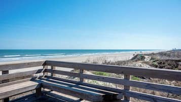 A wooden bench overlooking a beach with a clear view of the ocean and a road sign indicating route 39.