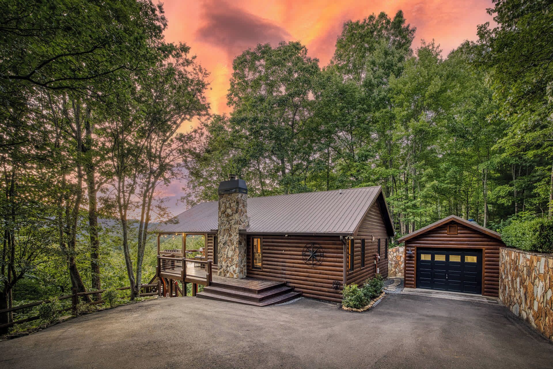 A log cabin with a stone chimney, a wooden porch, and a garage.