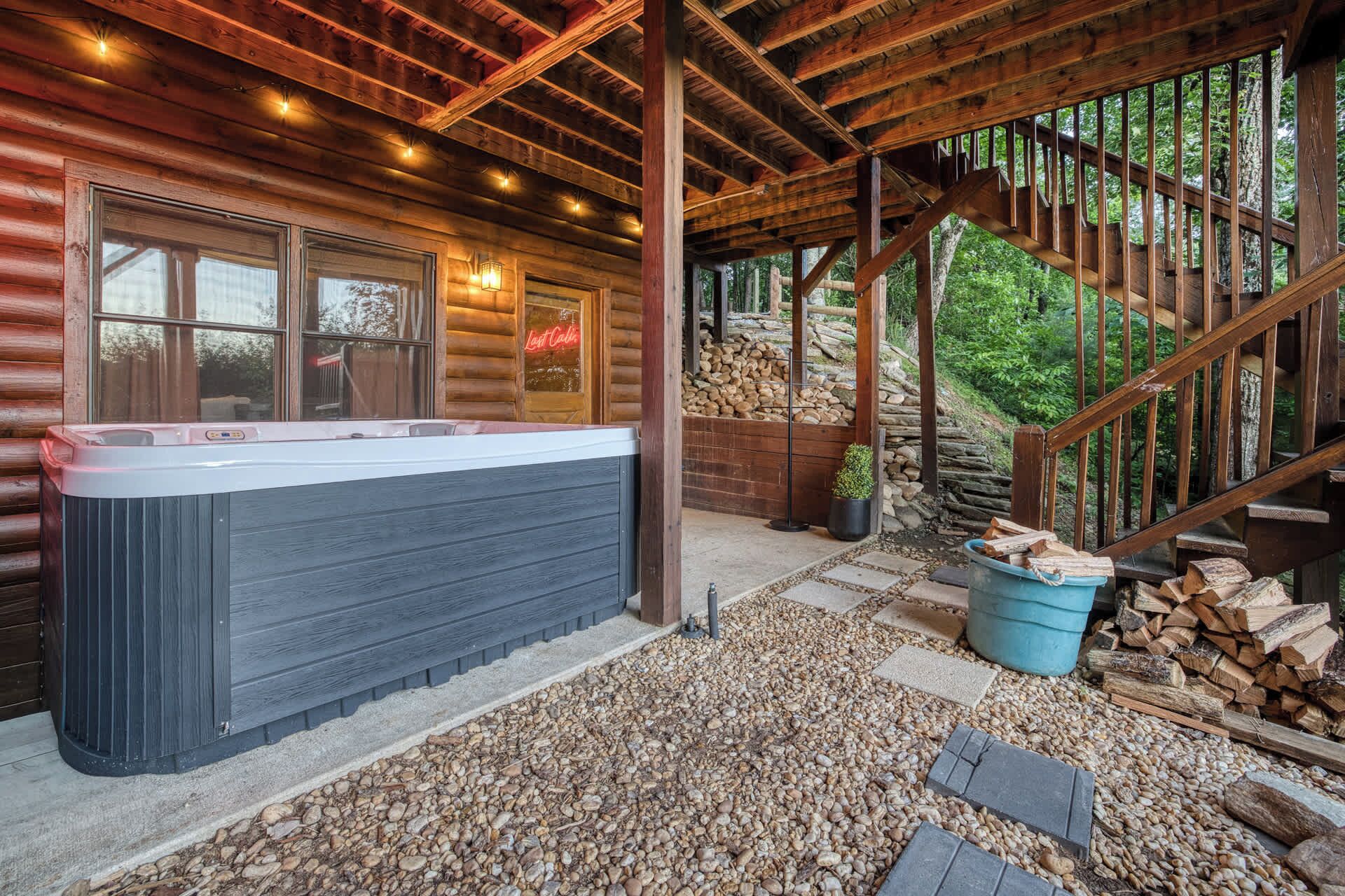 A hot tub in a log cabin with a stone staircase and a view of the forest.