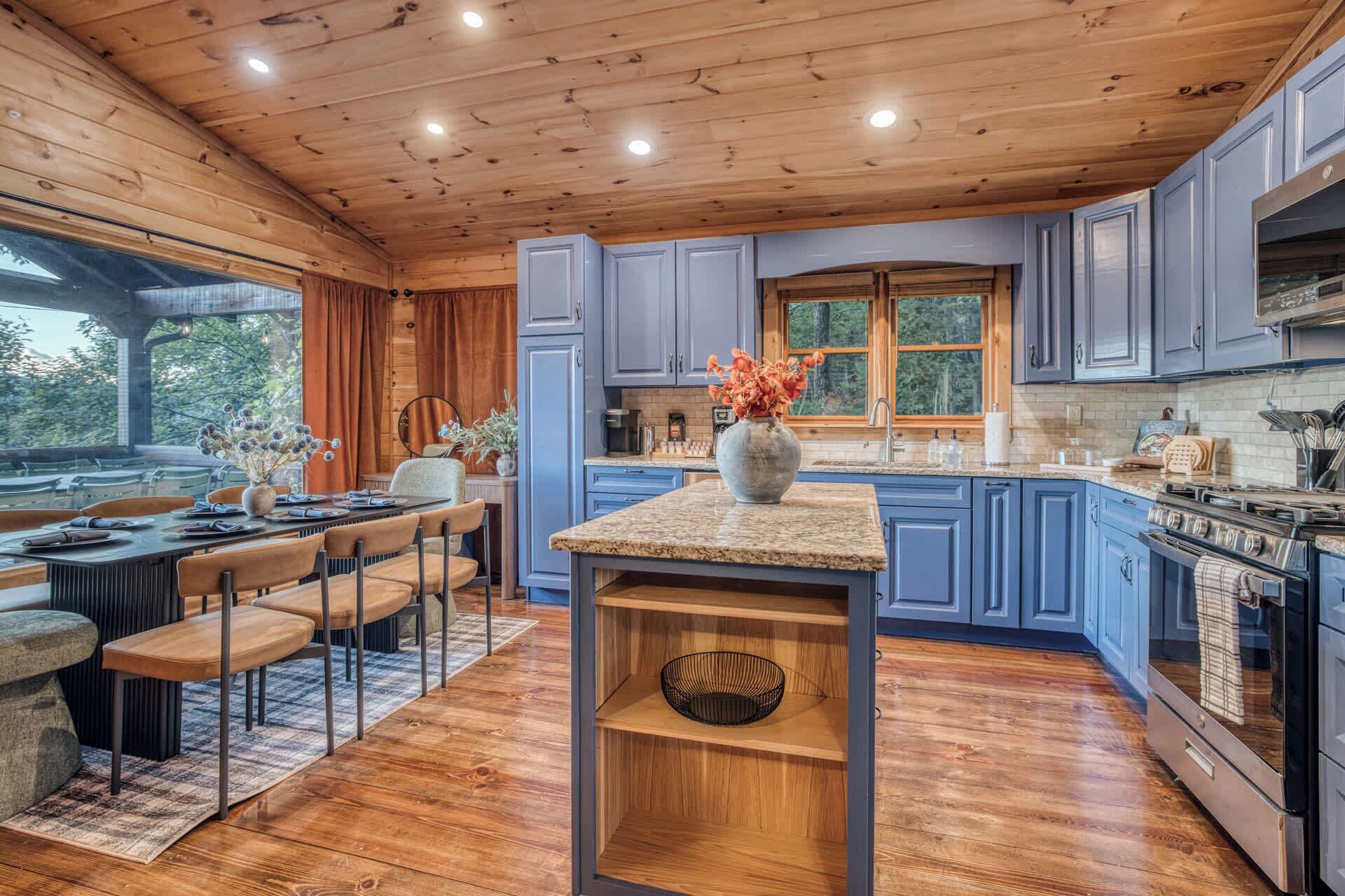 A modern kitchen with blue cabinets, a granite countertop, and a central island.