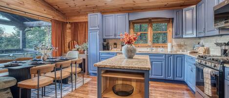 A modern kitchen with blue cabinets, a granite countertop, and a central island.