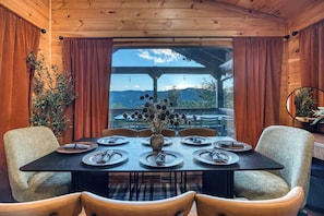 Un comedor con una mesa preparada para seis, paredes de madera y vistas al exterior.