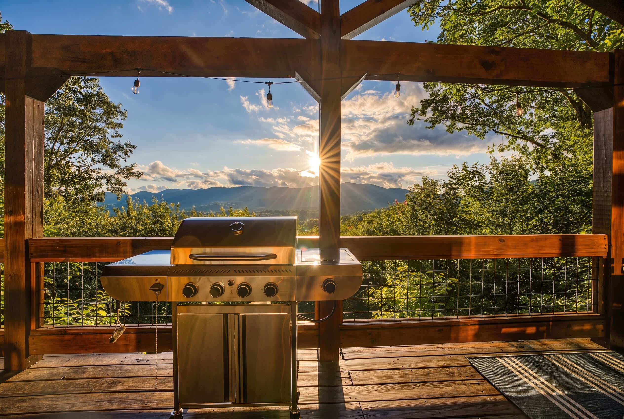 En träaltan med en grill, utsikt över bergen och en klar himmel.