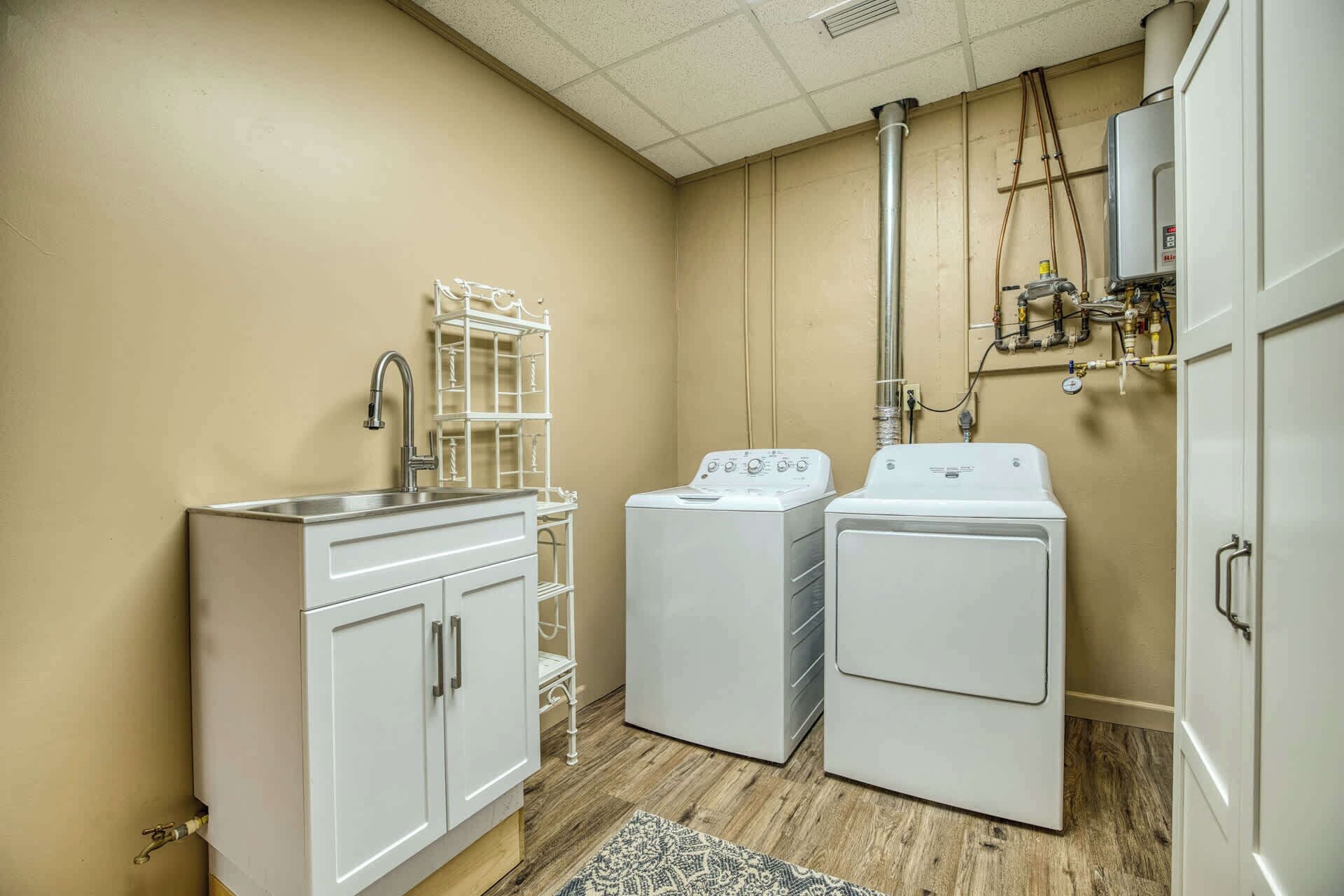 A laundry room with a sink, two washing machines, and a metal rack.