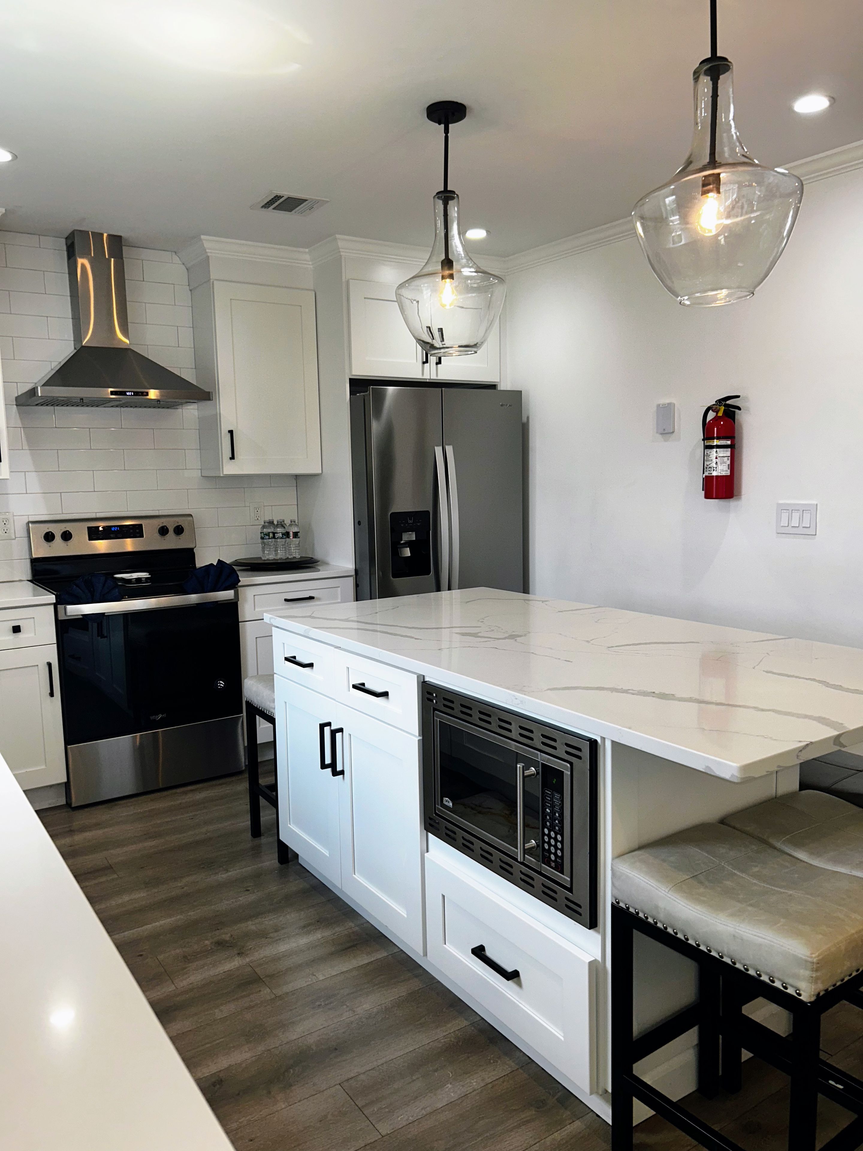 A modern kitchen with a central island, stainless steel appliances, and pendant lighting.
