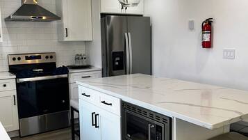 A modern kitchen with a central island, stainless steel appliances, and pendant lighting.