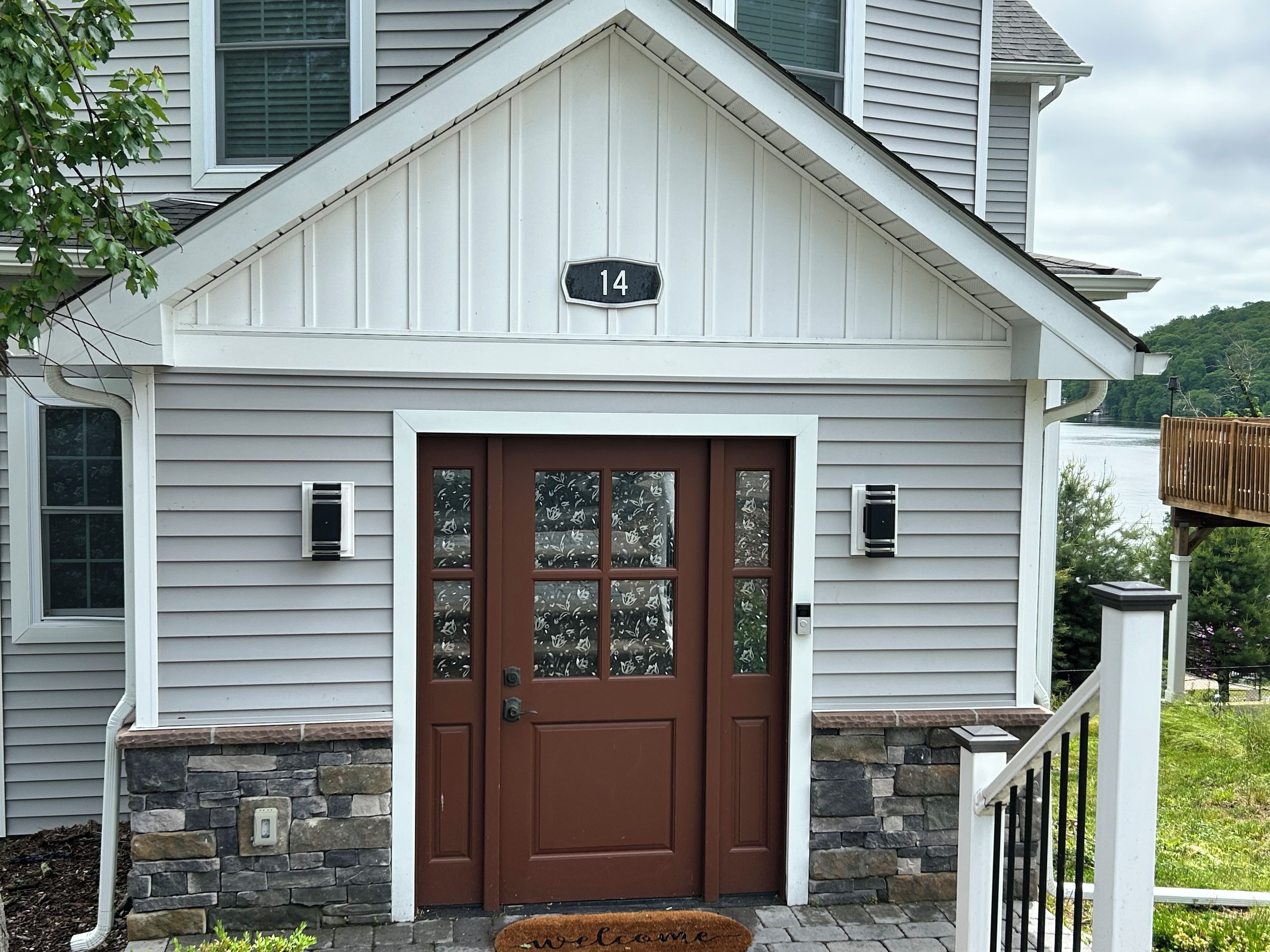 A house with a brown front door, a number 14 sign above it, and a stone base.