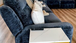 A modern living room with dark sofas, a white coffee table, and a remote control on the table. - Lux Lakeview Experience Sleep 8 (Hopatcong)