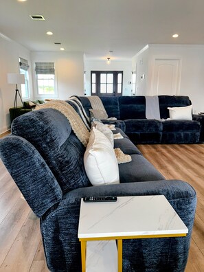 Een moderne woonkamer met donkere banken, een witte salontafel en een afstandsbediening op de tafel.