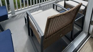 A balcony with a table and chairs, overlooking a lake with a view of trees and houses. - Lux Lakeview Experience Sleep 8 (Hopatcong)