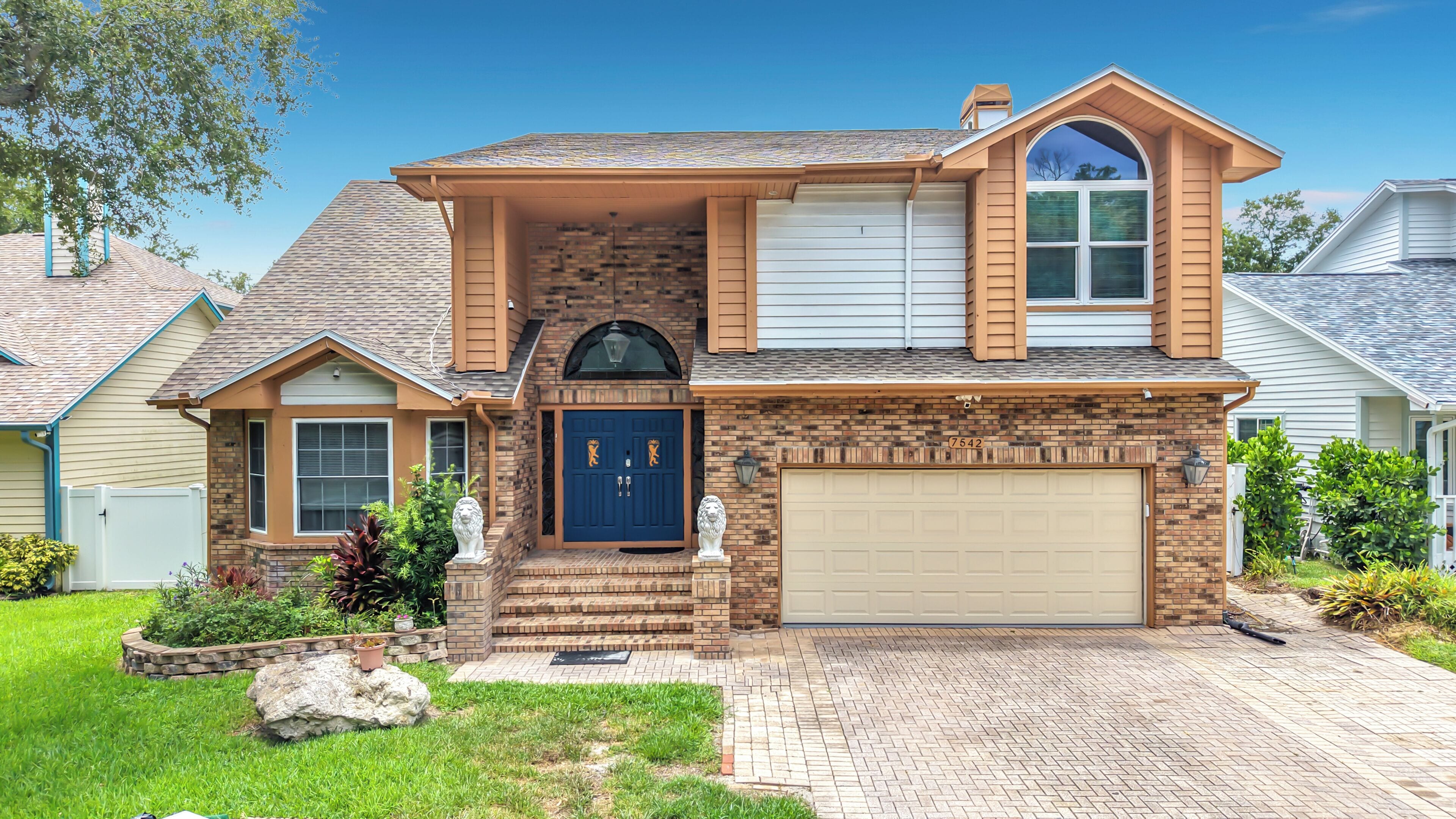 A two-story house with a brick facade, a blue front door, and a garage.