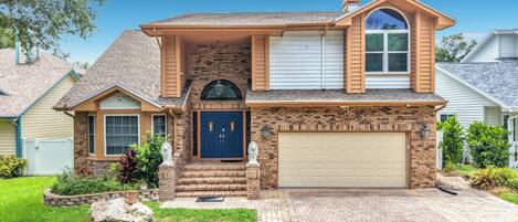 A two-story house with a brick facade, a blue front door, and a garage.