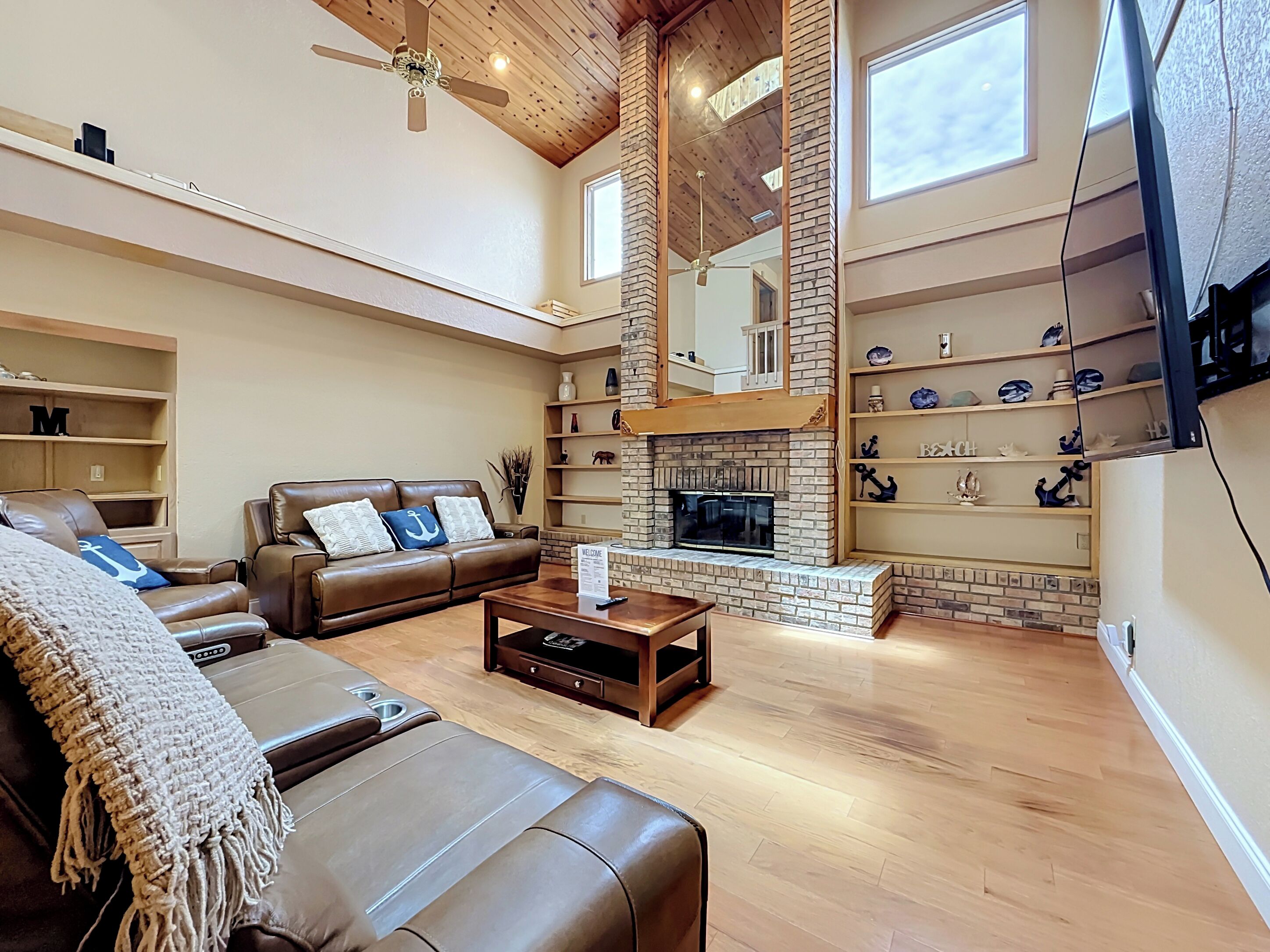 A spacious living room with a leather sofa, a coffee table, and a fireplace.