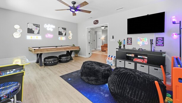 A modern living room with a pool table, gaming area, and a television. - Cayuga Clubhouse • Poolside Fun & Game Room (Jacksonville)