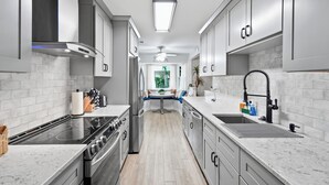 A modern kitchen with stainless steel appliances, white cabinetry, and a central island. - Cayuga Clubhouse • Poolside Fun & Game Room (Jacksonville)