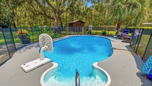 A swimming pool with a hot tub, surrounded by a fence and trees. - Cayuga Clubhouse • Poolside Fun & Game Room (Jacksonville)