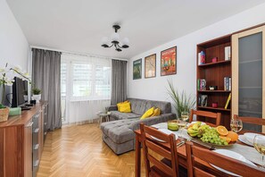 A modern living room with a grey sofa, wooden dining table, and a bookshelf. - House in Landunvez Near Penfoul Beach (Warsaw)