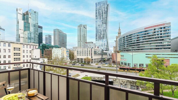 A balcony with a table set for two, overlooking a cityscape with modern buildings and a clear sky. - House in Landunvez Near Penfoul Beach (Warsaw)
