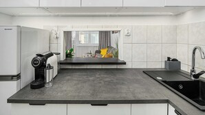 A modern kitchen with a built-in coffee maker, a sink, and a window with curtains. - House in Landunvez Near Penfoul Beach (Warsaw)