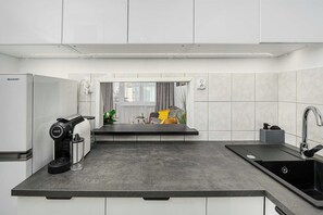 Eine moderne Küche mit integrierter Kaffeemaschine, einem Spülbecken und einem Fenster mit Vorhängen.