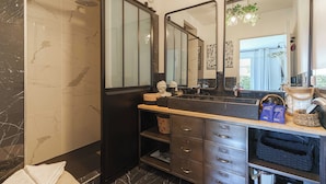 A bathroom with a double vanity, a large mirror, a shower, and a towel rack. - Flat in the Heart of Deauville With a Garden (Deauville)