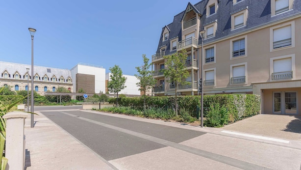 A residential street with modern apartment buildings, a clear sky, and a pedestrian pathway. - Flat in the Heart of Deauville With a Garden (Deauville)